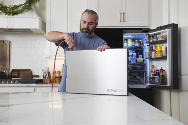 Man plugging Blackout Buddy into kitchen fridge