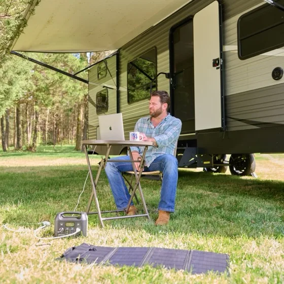 Patriot Power Sidekick powering a laptop outside an RV with the optional 40-Watt folding solar panel