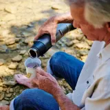A man pouring hot water from the Sun Kettle into a mug outdoors
